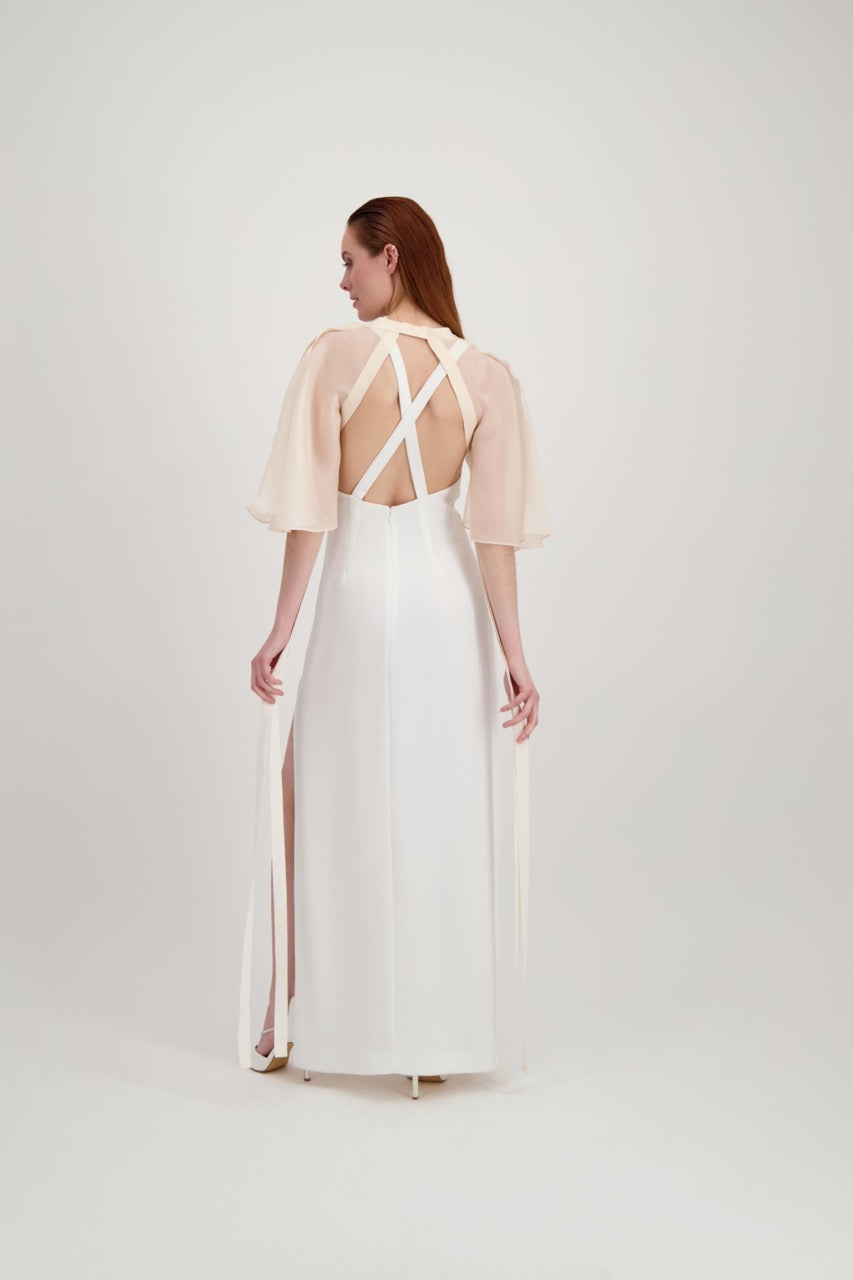 Jeune femme rousse de dos habillée d'une longue robe blanche et d'une cape rose poudrée avec des rubans de soie