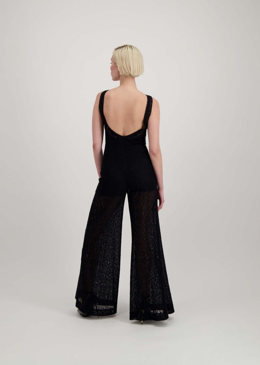 Femme de dos portant une combinaison noire en dentelle avec un dos nu.