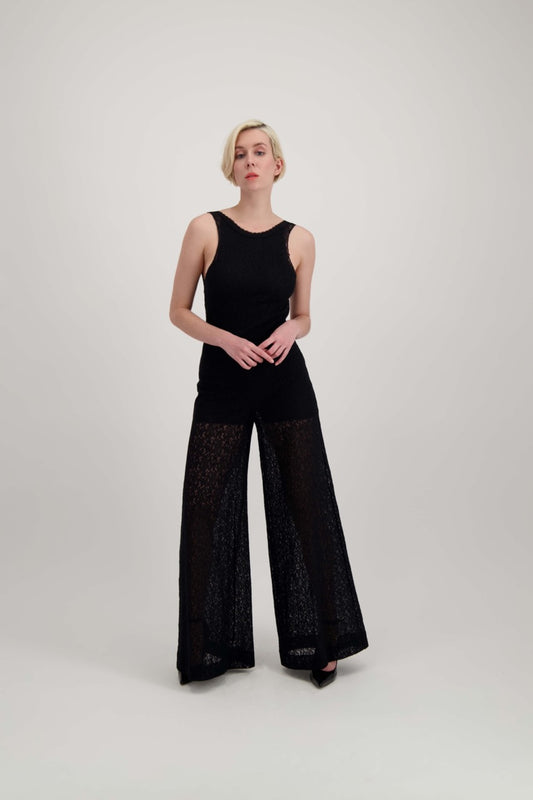Femme blonde portant une combinaison pantalon noire légèrement transparente