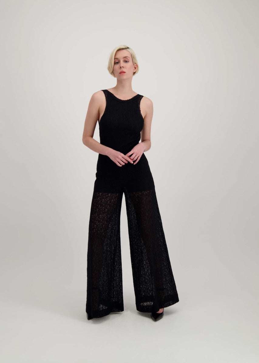 Femme blonde portant une combinaison pantalon noire légèrement transparente