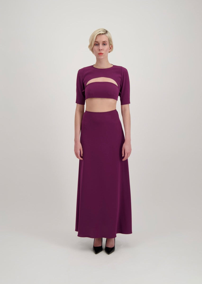 Femme avec un carré blond habillée d'un ensemble composé d'un boléro, d'un bandeau et d'une jupe lila
