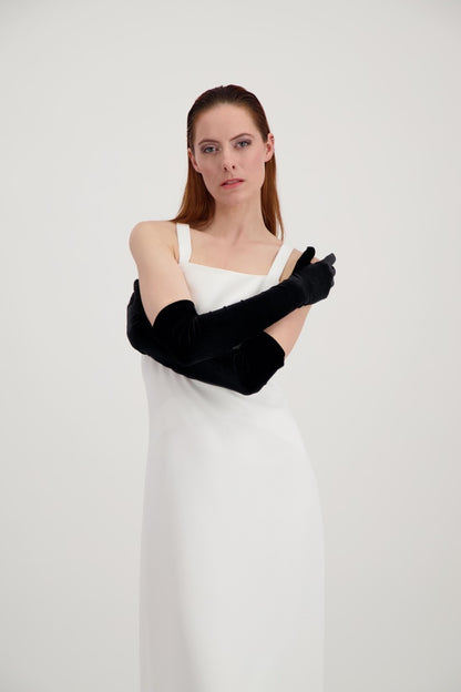 Jeune femme rousse, les bras croisés, habillée d'une robe blanche et de longs gants noirs en velours