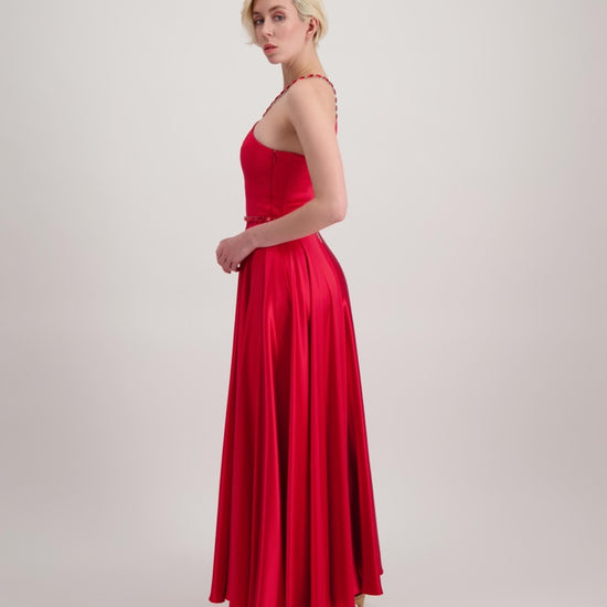 Jeune femme blonde qui tourne sur elle-même avec une longue robe du soir rouge qui tourne beaucoup