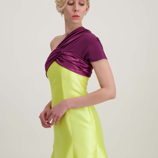 Jeune femme blonde qui marche habillée d'une robe longue du soir asymétrique en violet et jaune