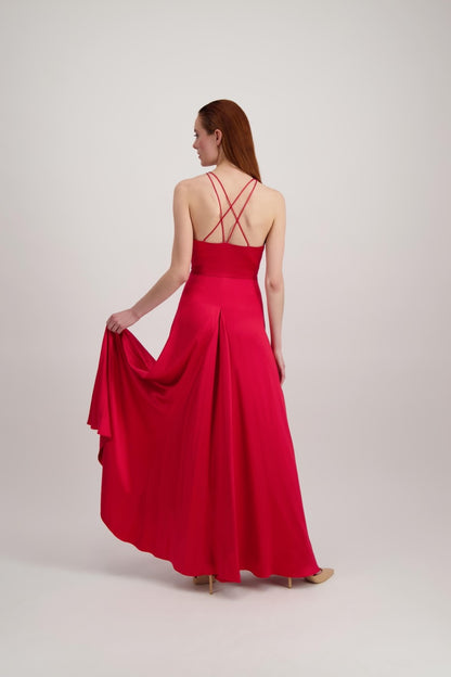Jeune femme rousse qui marche avec une longue robe rouge très évasée en bas et un dos ouvert où se croisent de fines bretelles