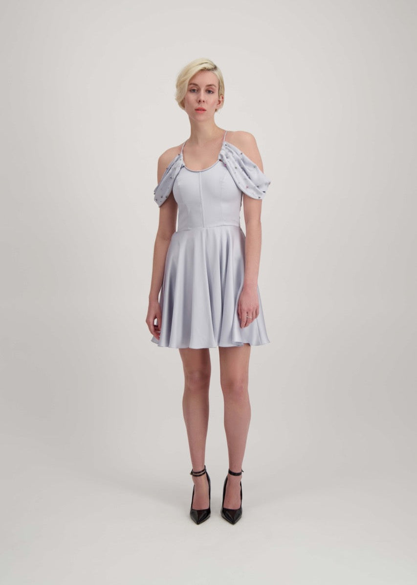 Jeune femme blonde habillée d'une robe coktail courte de couleur argent avec des strass sur les épaules