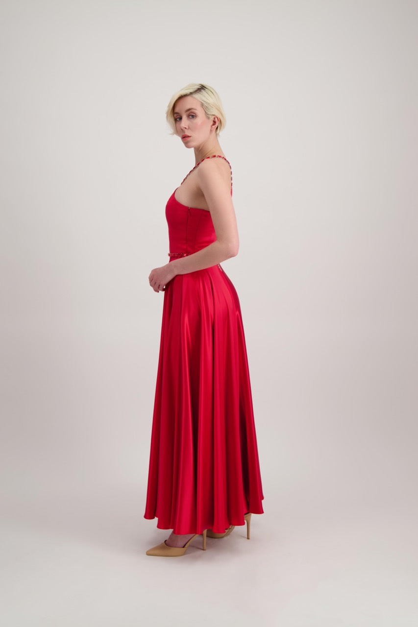Jeune femme blonde de profil habillée d'une robe longue asymétrique rouge avec des détails bijoux