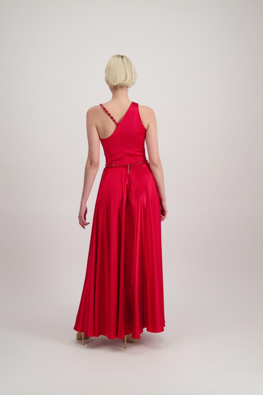 Jeune femme blonde de dos habillée d'une robe longue asymétrique rouge avec des détails bijoux