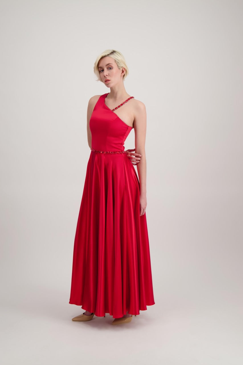 Jeune femme blonde habillée d'une robe longue asymétrique rouge avec des détails bijoux