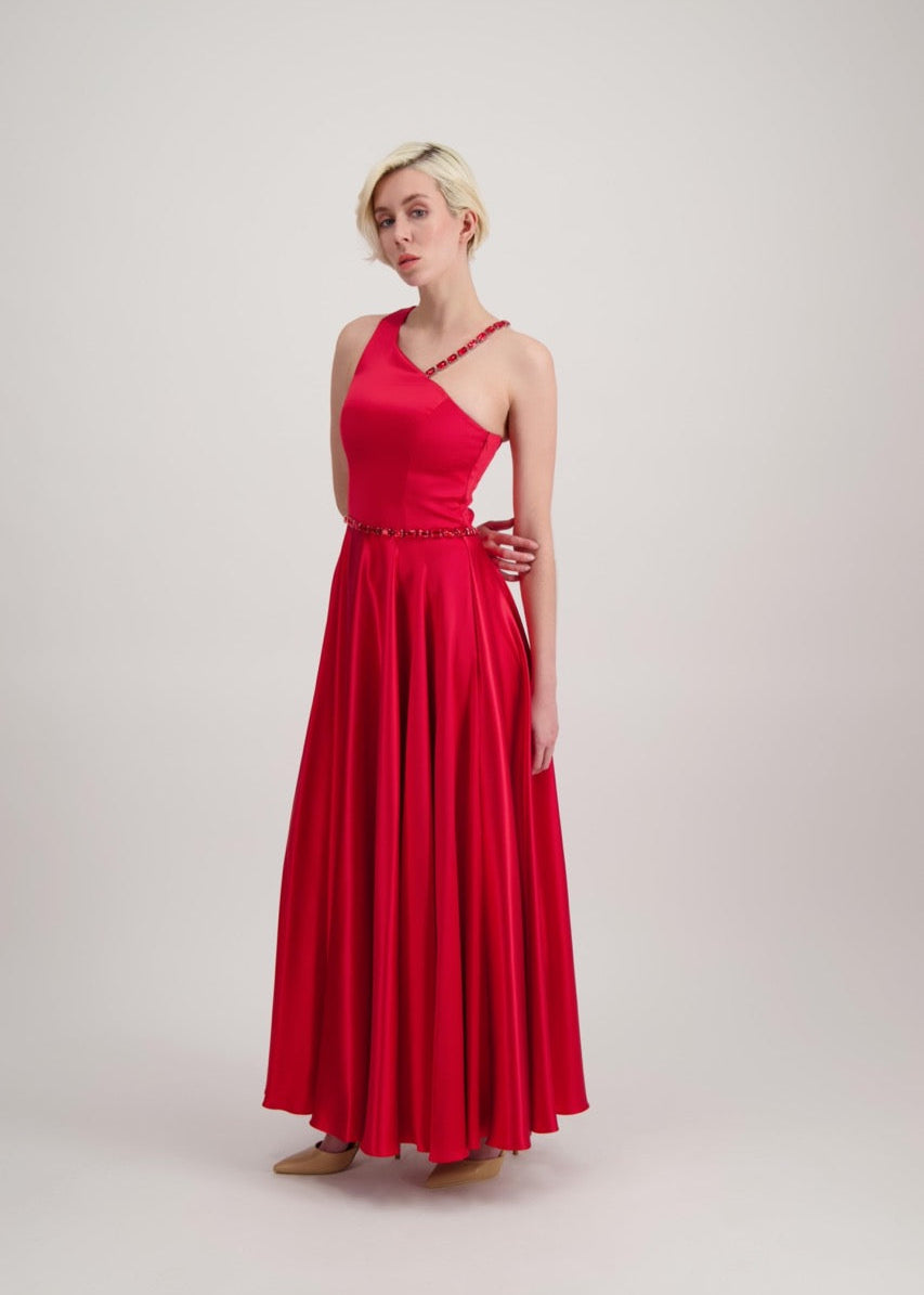 Jeune femme blonde habillée d'une robe longue asymétrique rouge avec des détails bijoux création SADEONE COUTURE