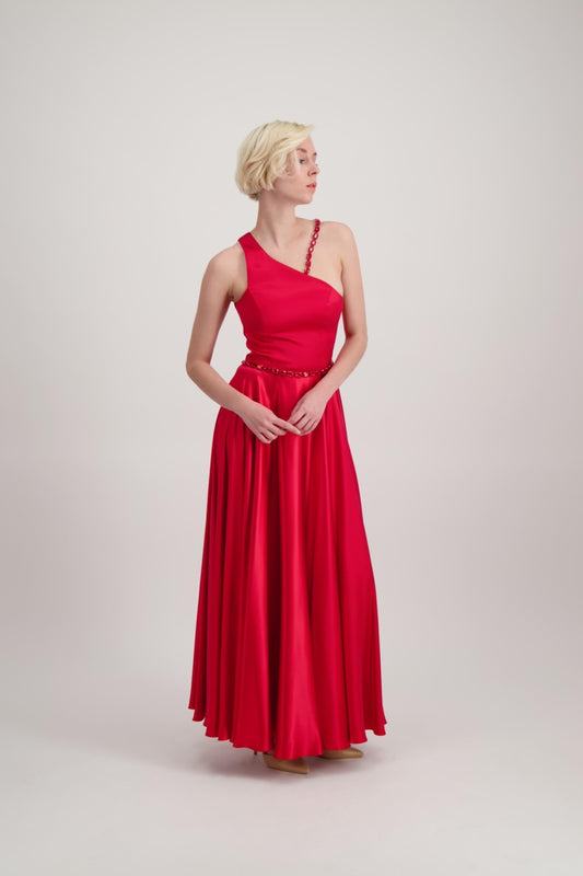 Jeune femme blonde habillée d'une robe longue asymétrique rouge avec des détails bijoux 
