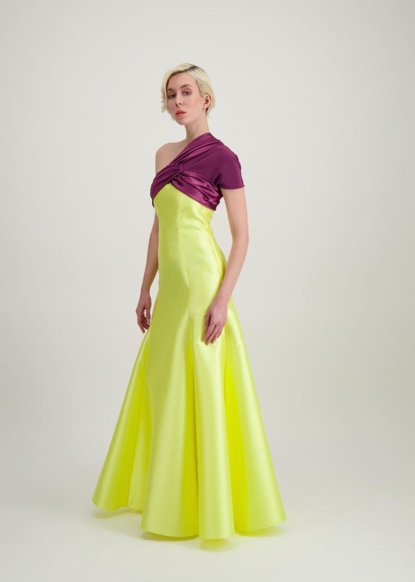 Jeune femme blonde de profil habillée d'une robe longue du soir asymétrique en violet et jaune