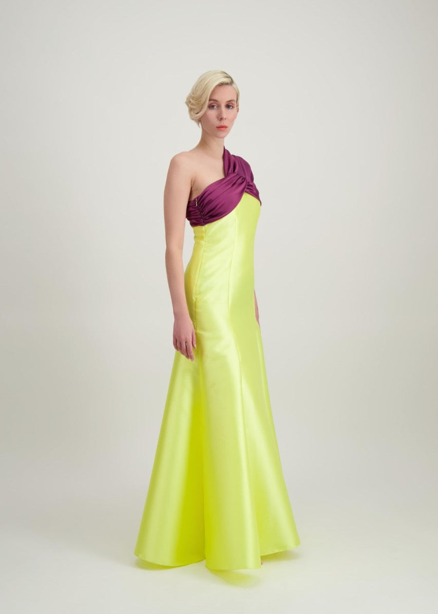 Jeune femme blonde de profil habillée d'une robe longue du soir asymétrique en violet et jaune