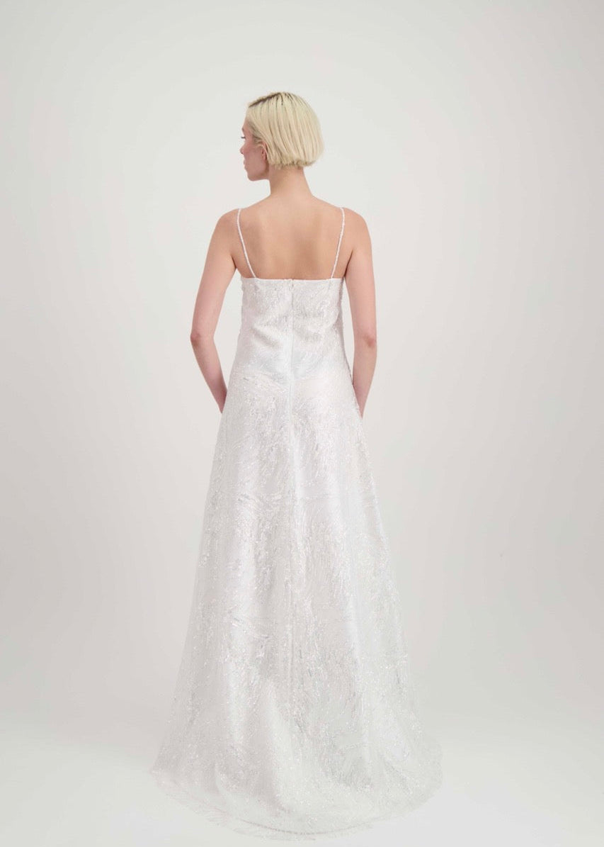 Jeune femme blonde de dos habillée d'une robe de mariée blanche à fines bretelles