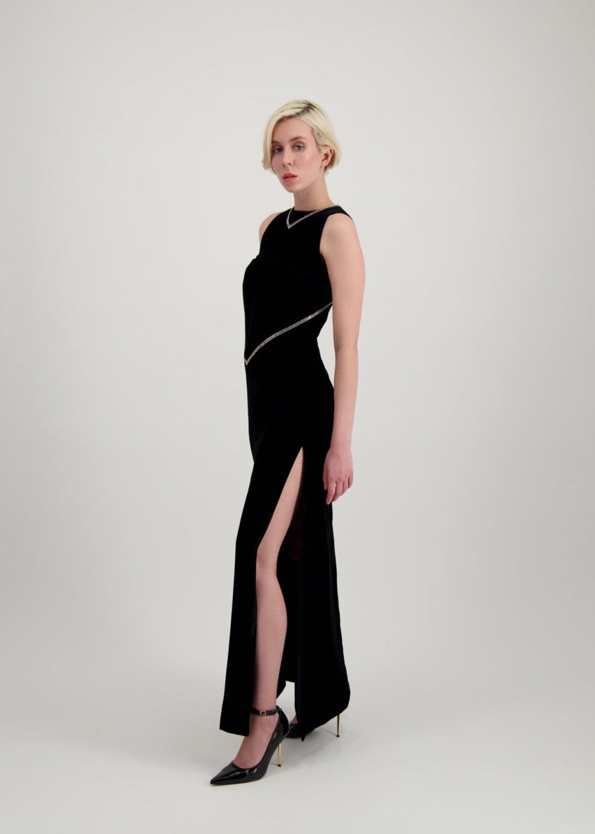 Jeune femme blonde de profil habillée d'une robe longue en velours noir avec des chevrons de strass et une fente
