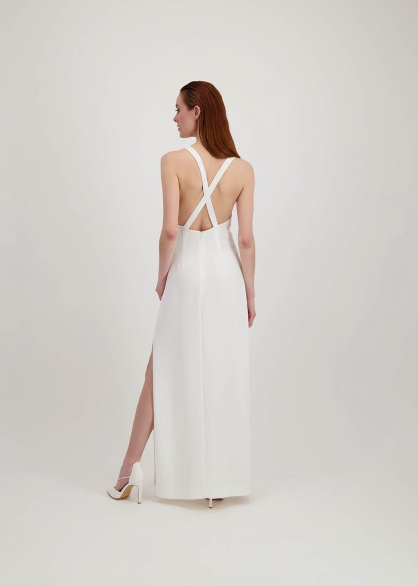 Jeune femme rousse de dos habillée d'une longue robe blanche avec une fente et un dos nu où se croisent des bretelles