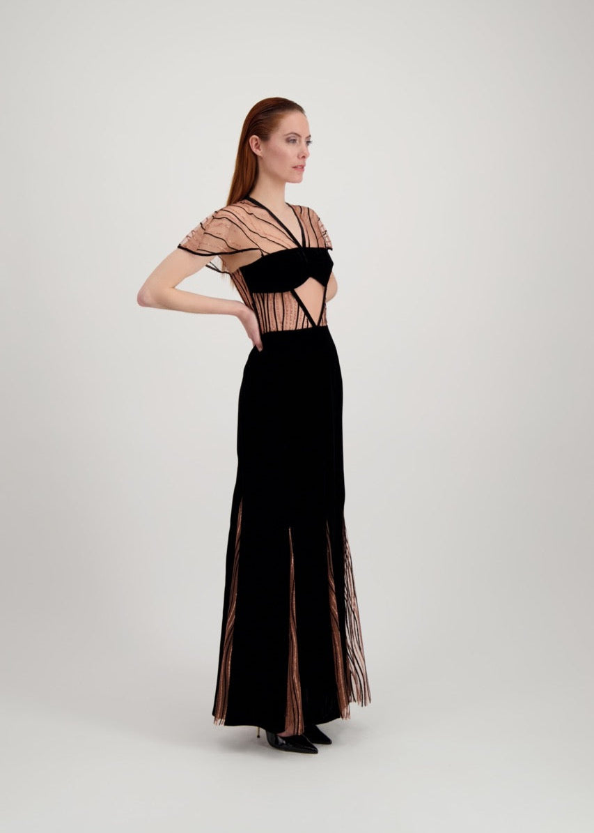 Jeune femme rousse de profil habillée d'une longue robe du soir en velours noir avec des motifs ondulés brillants.