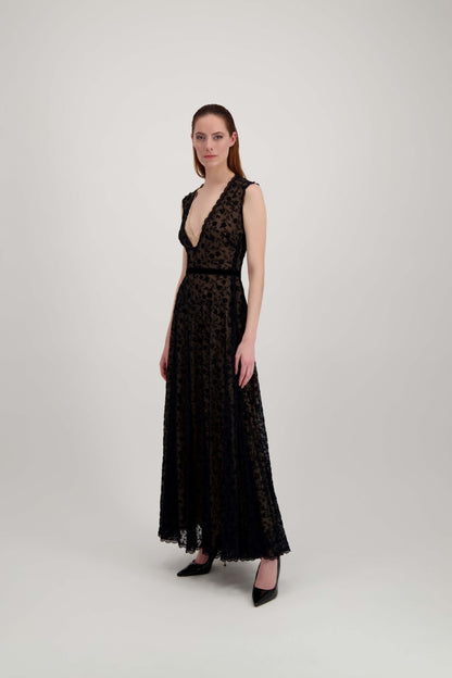 Jeune femme rousse de profil habillée d'une longue robe du soir en tulle et velours noir avec un grand décolleté en V.
