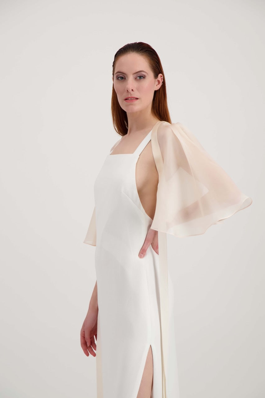 Jeune femme rousse de profil habillée d'une robe blanche et d'une cape rose poudrée avec des rubans de soie