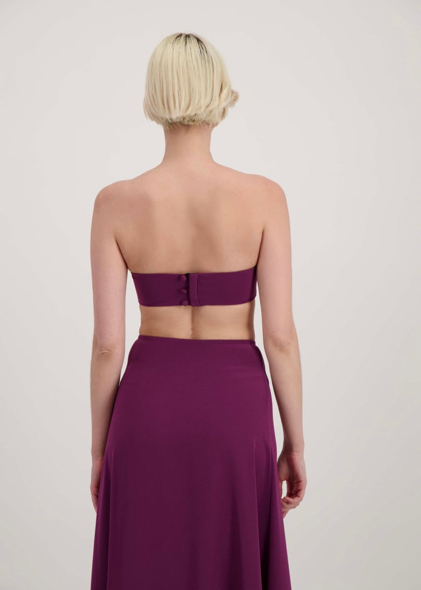 Femme blonde de dos habillée d'un ensemble lila avec un bandeau et une jupe