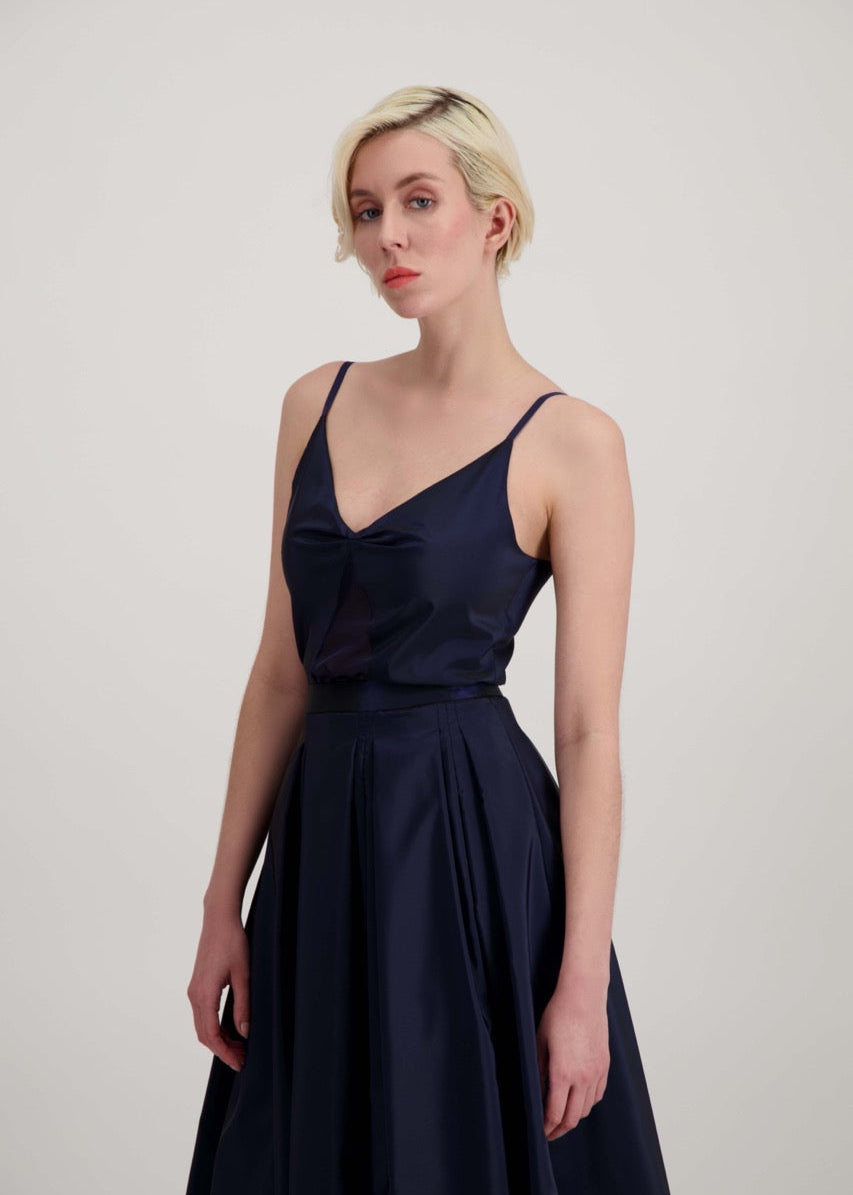 Femme blonde habillée d'un ensemble bleu marine avec une jupe et un débardeur