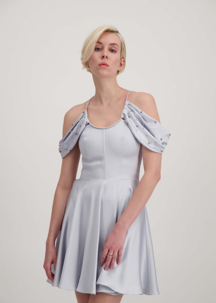 Jeune femme blonde habillée d'une robe coktail courte de couleur argent avec des strass sur les épaules