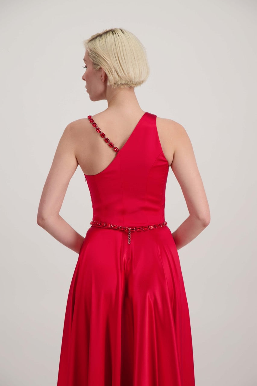 Jeune femme blonde de dos habillée d'une robe longue asymétrique rouge avec des détails bijoux