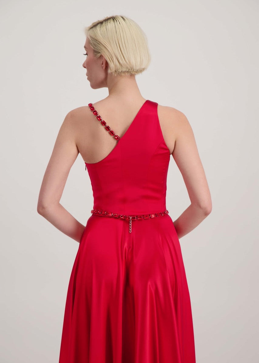 Jeune femme blonde de dos habillée d'une robe longue asymétrique rouge avec des détails bijoux création SADEONE COUTURE