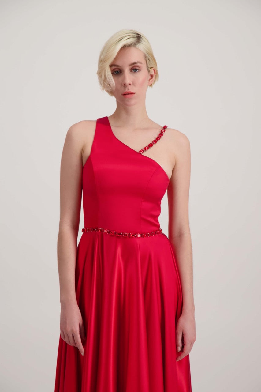 Jeune femme blonde habillée d'une robe longue asymétrique rouge avec des détails bijoux