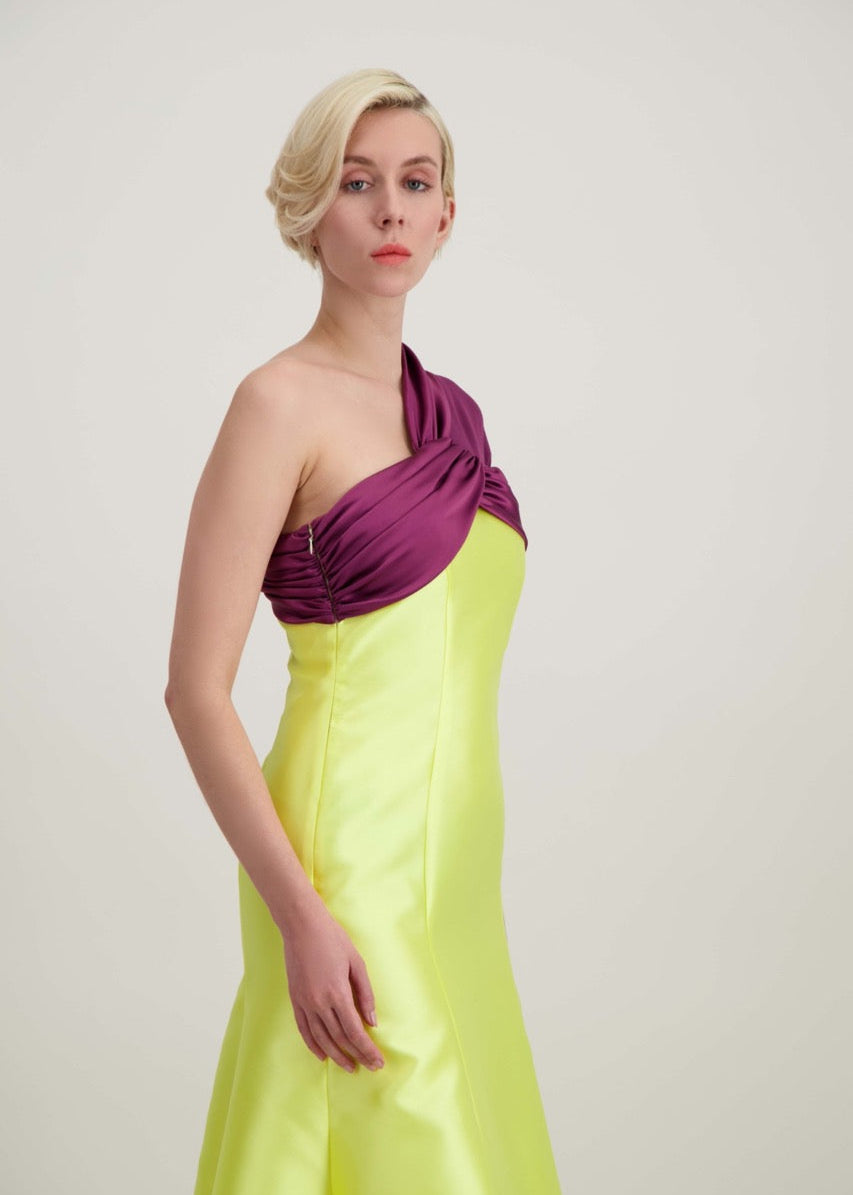 Jeune femme blonde de profil habillée d'une robe longue du soir asymétrique en violet et jaune