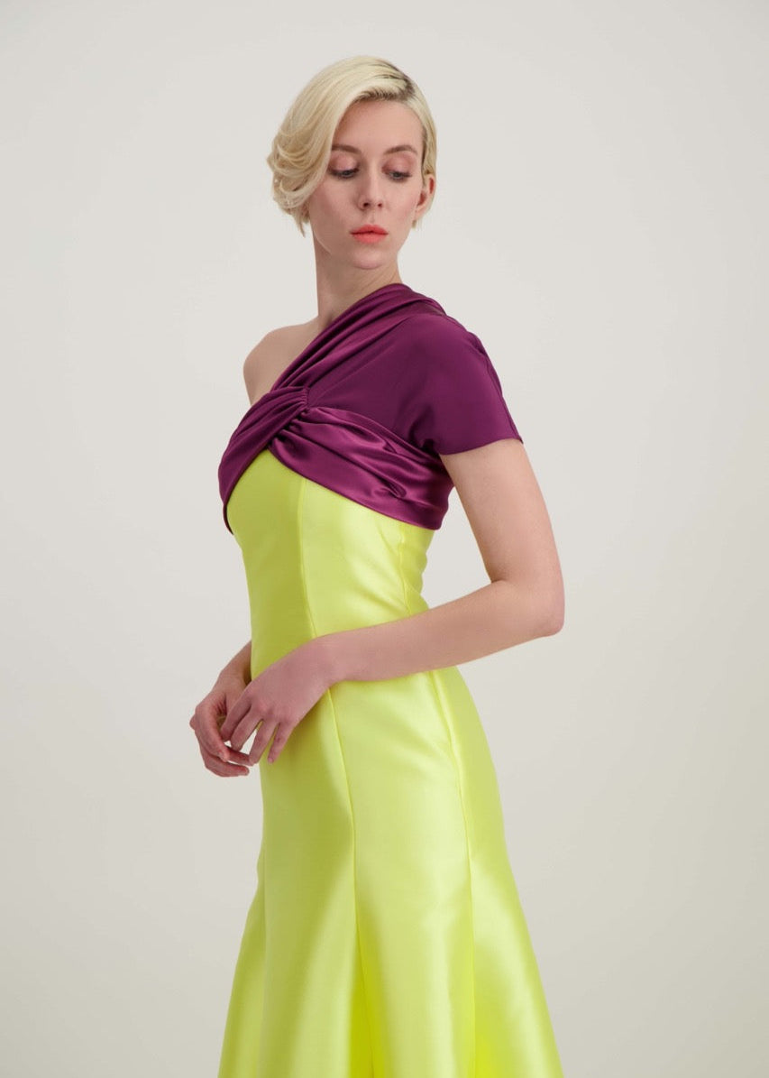 Jeune femme blonde de profil habillée d'une robe longue du soir asymétrique en violet et jaune