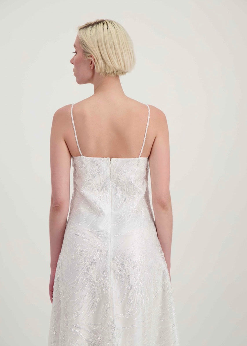 Jeune femme blonde de dos habillée d'une robe de mariée blanche à fines bretelles