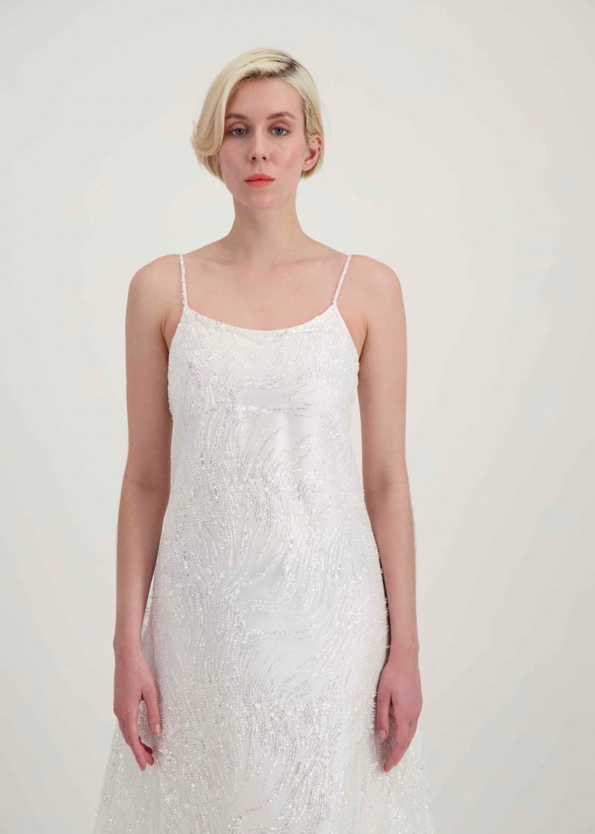 Jeune femme blonde habillée d'une robe de mariée blanche à fines bretelles