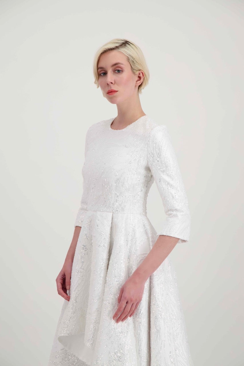 Jeune femme blonde habillée d'une robe de mariée blanche avec des manches 3/4