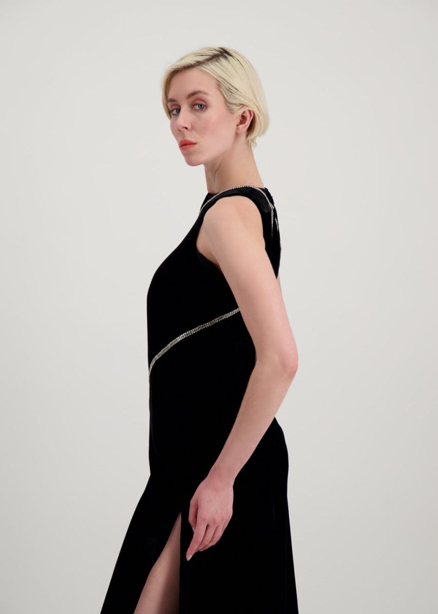 Jeune femme blonde de profil habillée d'une robe longue en velours noir avec des chevrons de strass et une fente