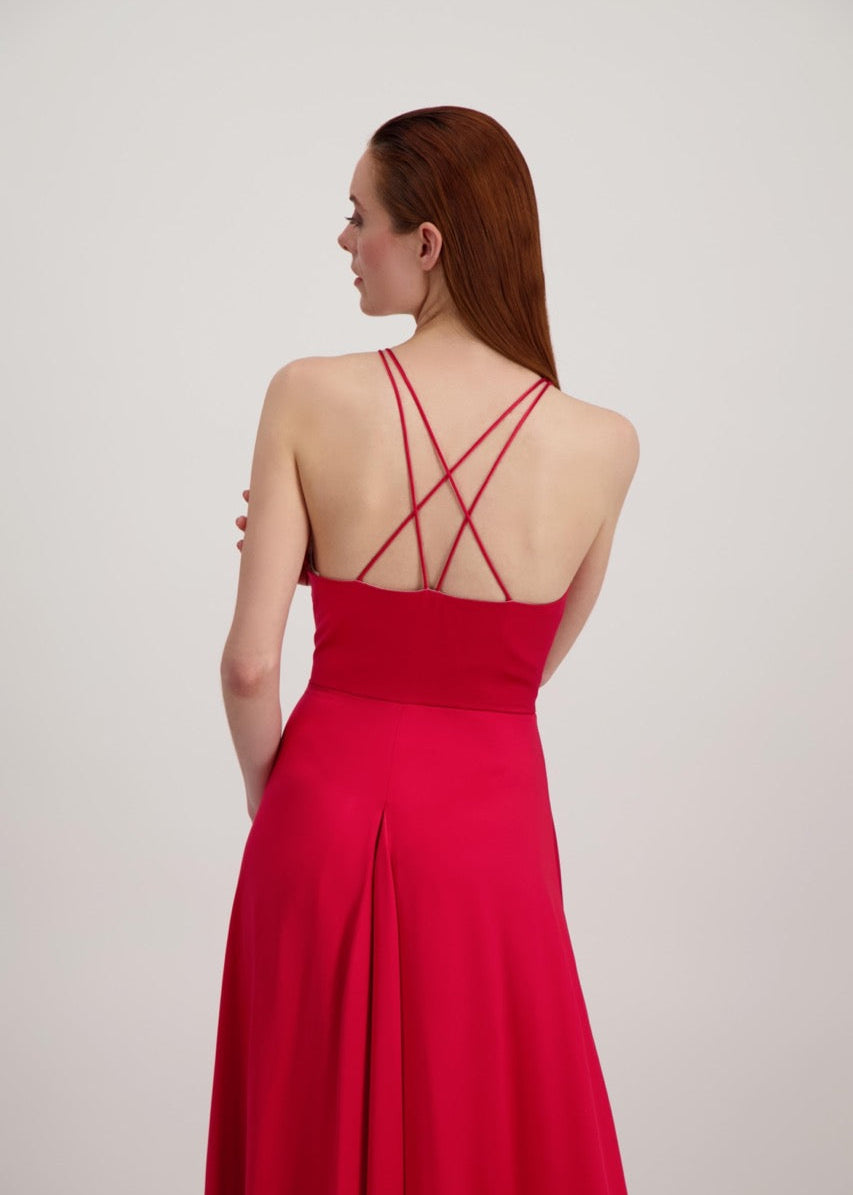 Jeune femme rousse de dos habillée d'une longue robe rouge avec dos ouvert sur des bretelles croisées