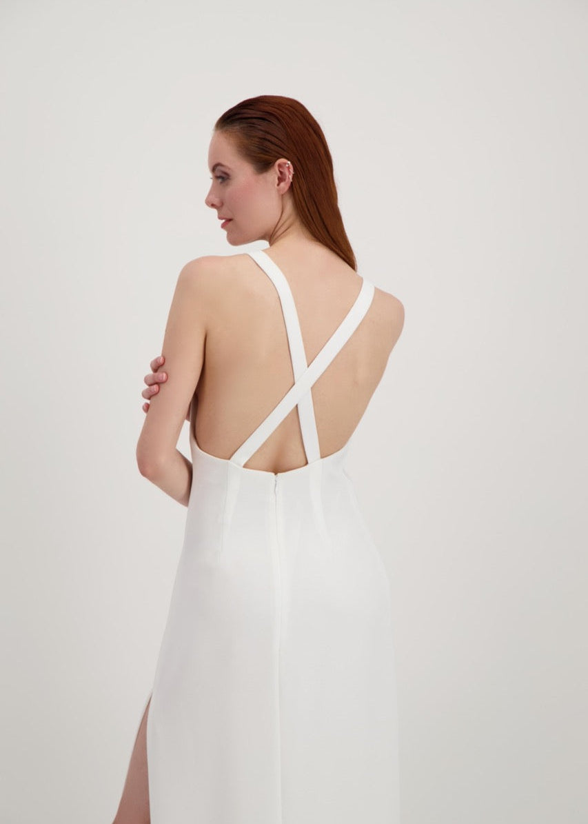 Jeune femme rousse habillée d'une longue robe blanche avec un dos nu ouvert sur des bretelles qui se croisent