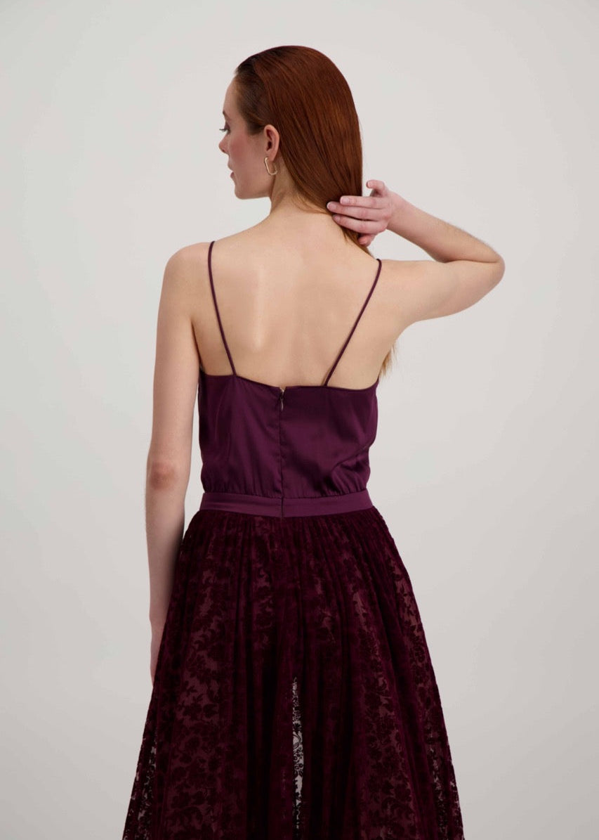 Jeune femme rousse de dos habillée d'une robe à bretelles bordeaux avec des motifs fleuris en velours sur le bas