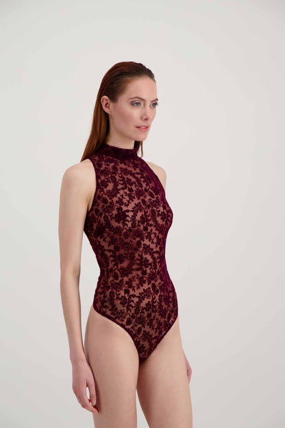 Jeune femme rousse, de profil, habillée d'un body bordeaux ras-du-cou avec des motifs floraux en velours