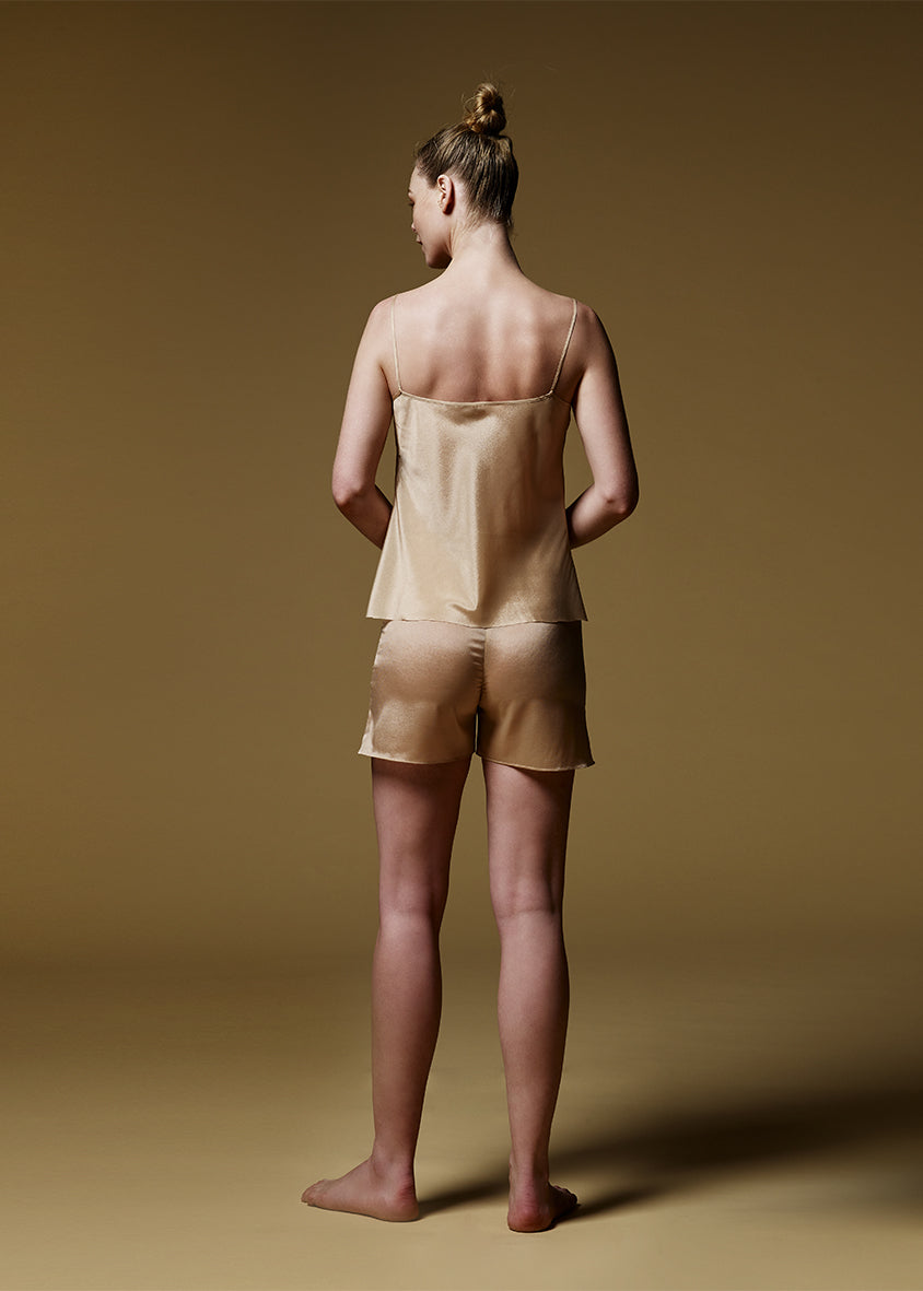 Jeune femme de dos habillée d'un short et d'un débardeur en soie beige