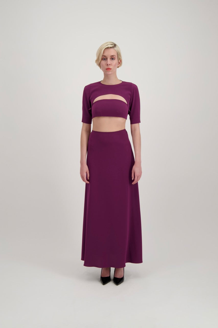 Femme avec un carré blond habillée d'un ensemble composé d'un boléro, d'un bandeau et d'une jupe lila