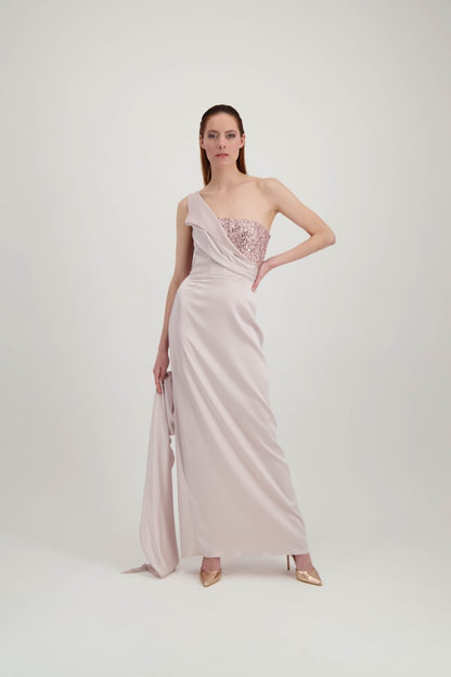 Jeune femme rousse habillée d'une longue robe rose avec un bustier pailleté et une traîne partant de l'épaule