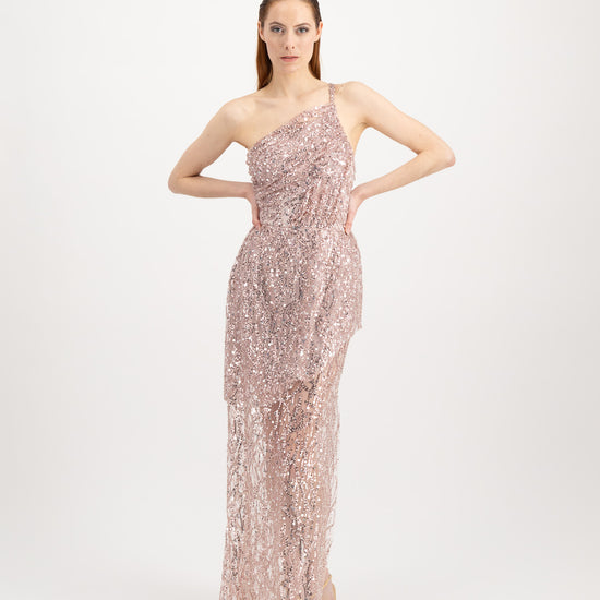 Jeune femme rousse qui défile avec une longue robe du soir rose brillante asymétrique et avec une fente