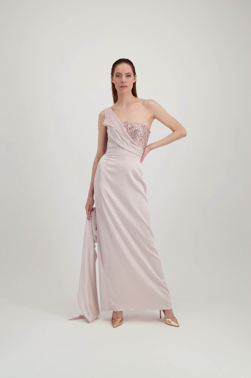 Jeune femme rousse avec une main à la taille qui porte une longue robe rose avec une étole qui finit en traîne