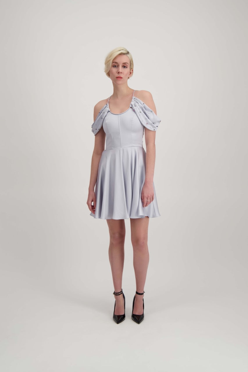 Jeune femme blonde habillée d'une robe coktail courte de couleur argent avec des strass sur les épaules
