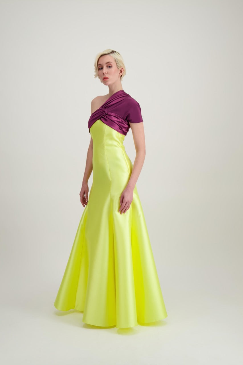 Jeune femme blonde de profil habillée d'une robe longue du soir asymétrique en violet et jaune