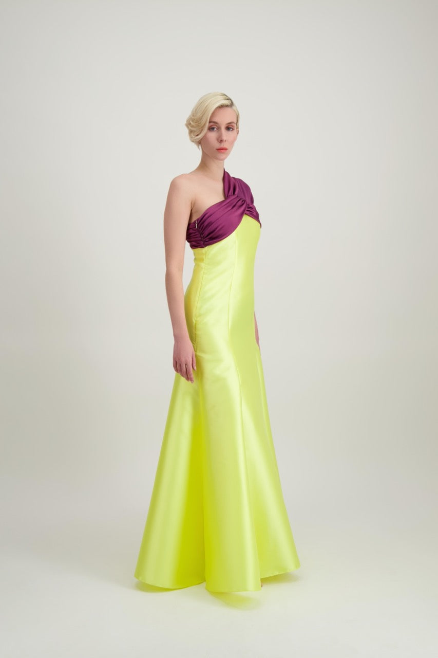 Jeune femme blonde de profil habillée d'une robe longue du soir asymétrique en violet et jaune