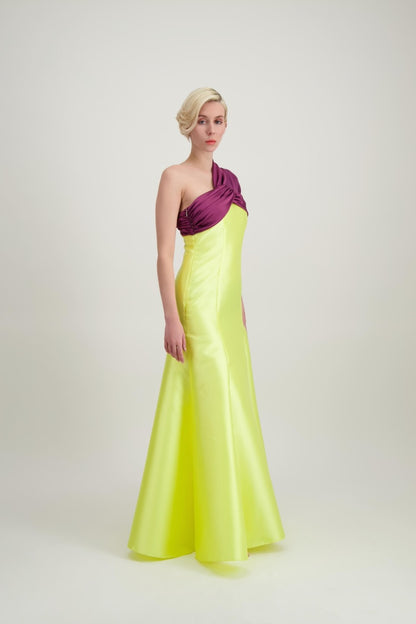 Jeune femme blonde de profil habillée d'une robe longue du soir asymétrique en violet et jaune