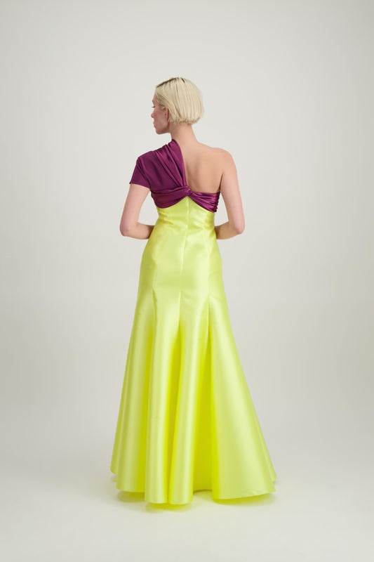 Jeune femme blonde de dos habillée d'une robe longue du soir asymétrique en violet et jaune
