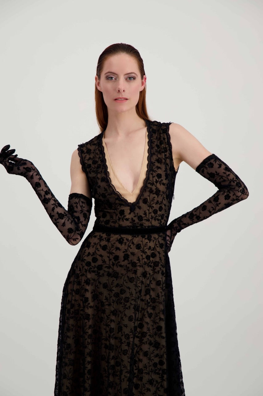 Jeune femme rousse habillée d'une robe en dentelle noire et d'une paire de longs gants assortis. 